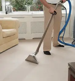 Professional carpet cleaner using a hot-water extraction wand and hose machine in a living room in Columbia, SC.