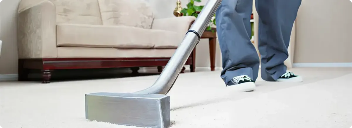 Carpet cleaning technician using a hot-water extraction wand on a light-colored carpet in a living room, Columbia, SC.