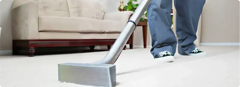 Carpet cleaning technician using a hot-water extraction wand on a light-colored carpet in a living room, Columbia, SC.