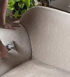Professional upholstery cleaner deep-cleaning a fabric sofa with a handheld extraction tool and hose Columbia, SC.